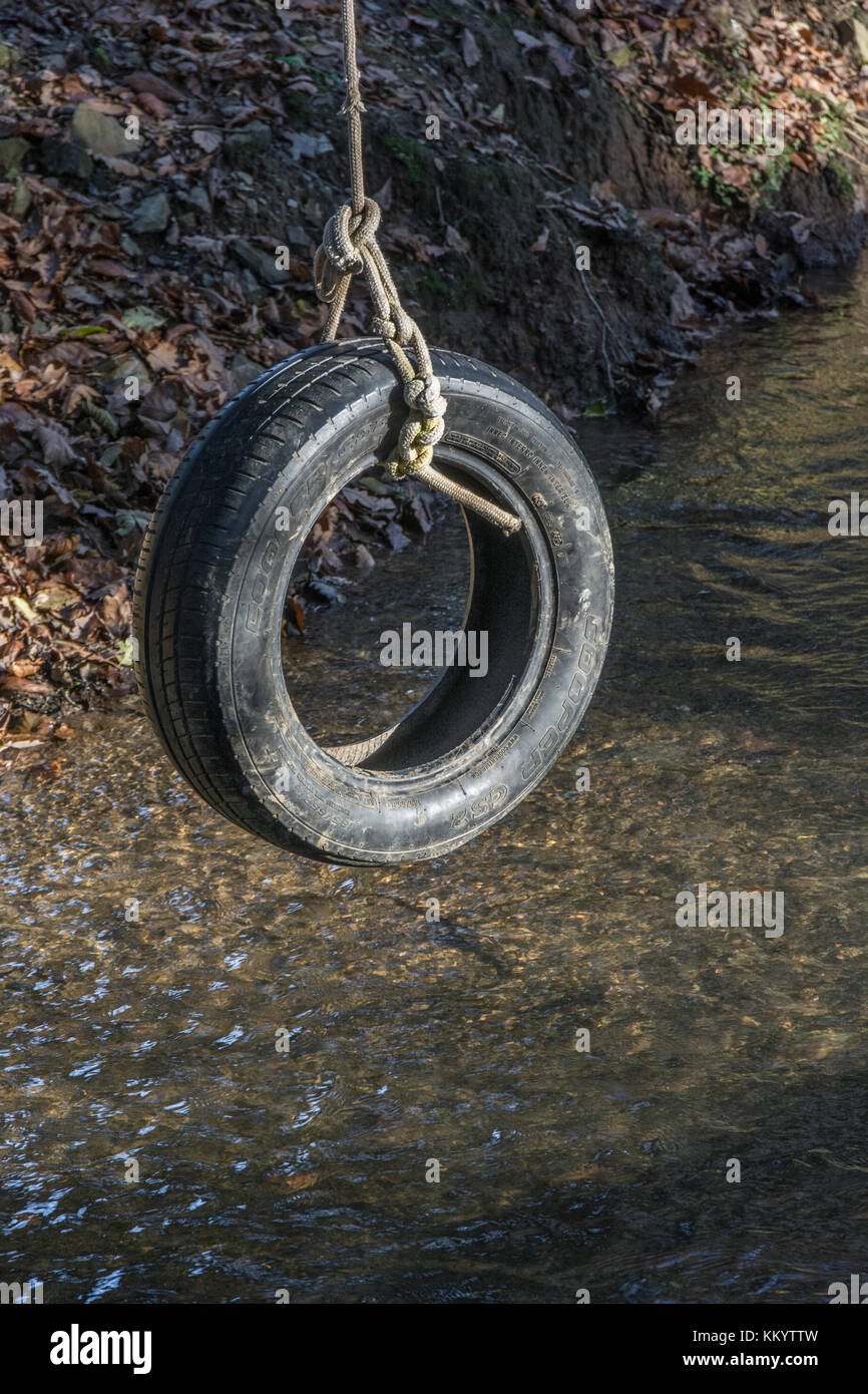 Balancement de pneu de voiture ancienne / balancement de pneu au repos sur un ruisseau de pays - rappelle l'un de l'amusement d'enfance et aussi la métaphore pour les balançoires de pendule. Banque D'Images