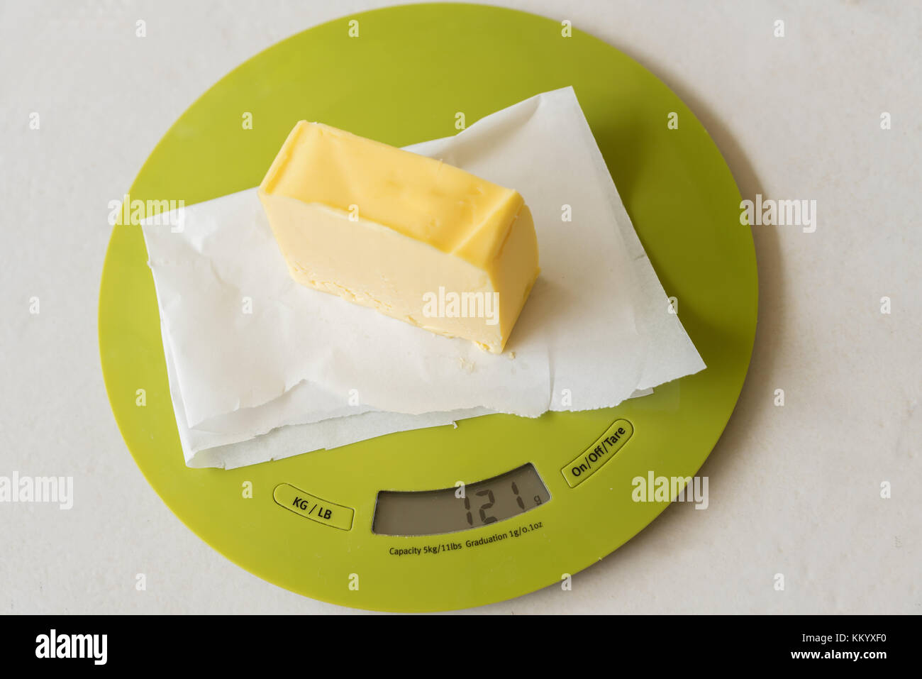 Tranche de beurre sur du papier huilé sur balance de cuisine numérique Banque D'Images