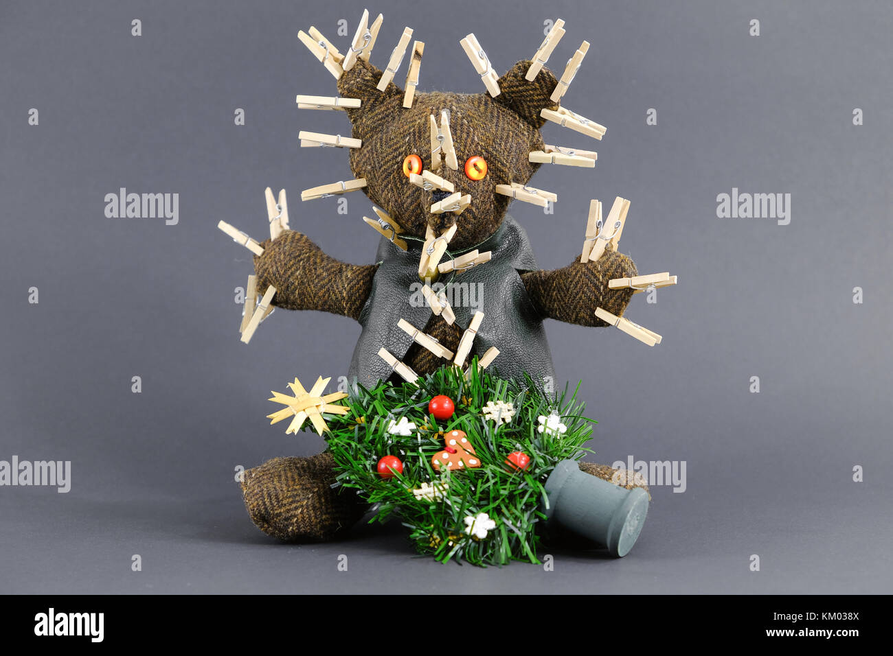 Un ours en peluche avec de nombreux clips blanchisserie pincé en il est titulaire d'un petit arbre de Noël artificiel. Banque D'Images