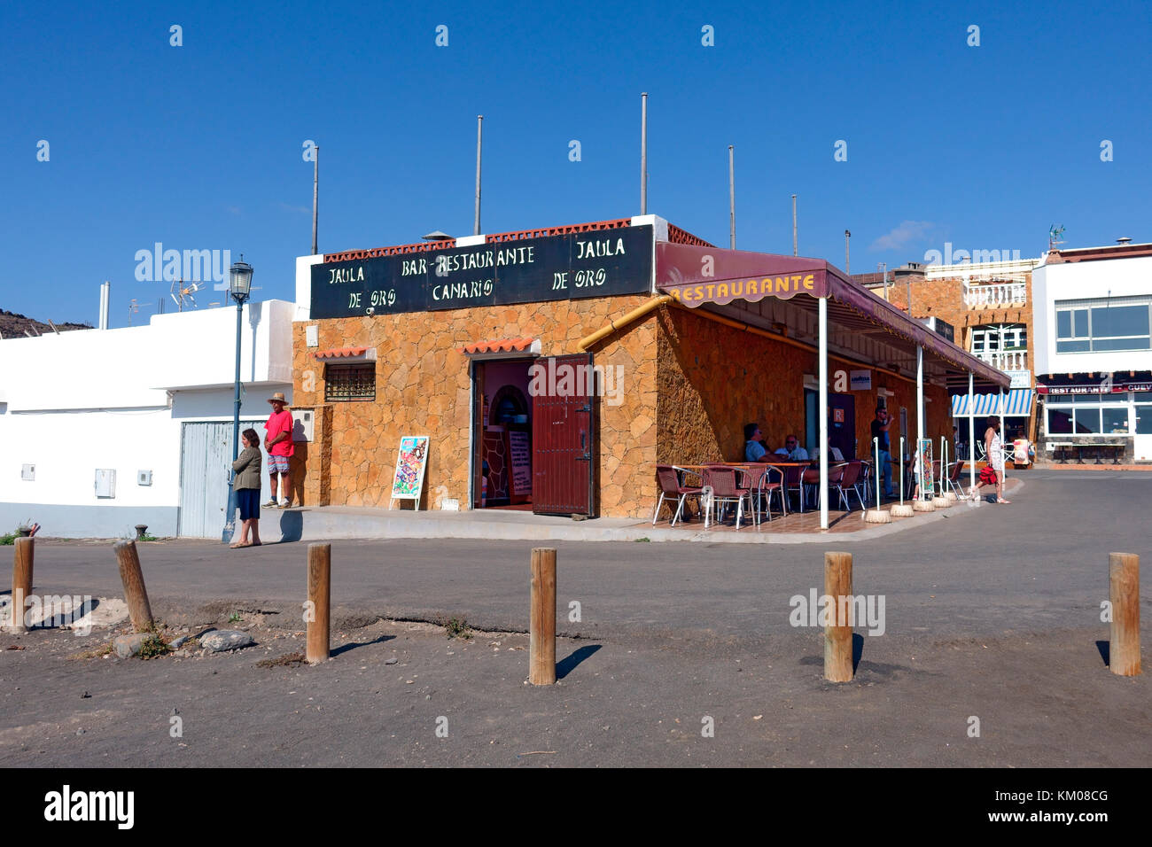 Restaurant à la façade de la plage à Ajuy, sur l'île des Canaries de Fuerteventura. Les bornes arrêtent les voitures qui délovent la route sur le sable noir. Banque D'Images
