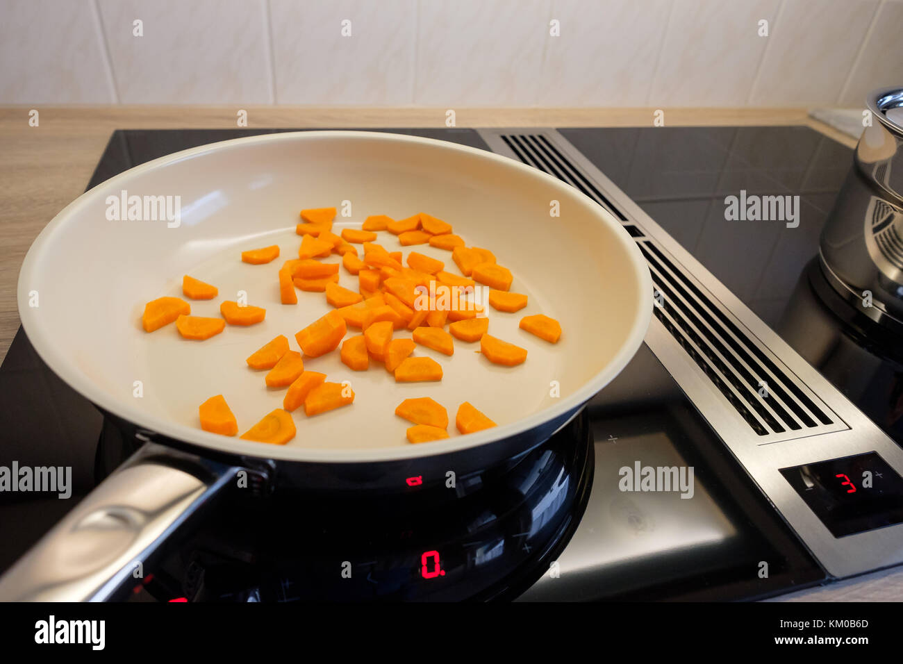 Les carottes dans une casserole sur une cuisinière à induction en vue de côté Banque D'Images