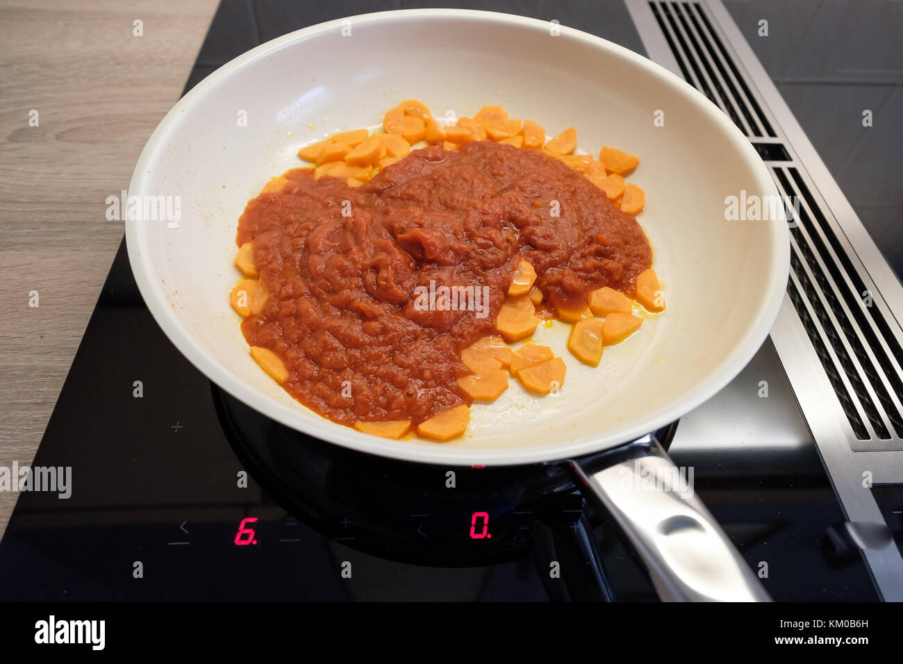 Les carottes et la sauce tomate dans une casserole sur une cuisinière à induction Banque D'Images