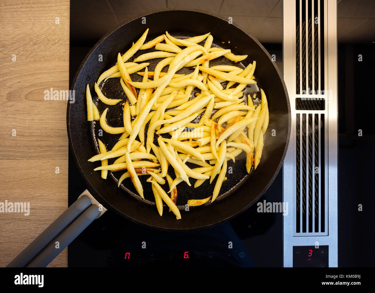 En forme de doigt boulettes de pommes de terre dans une poêle en fonte sur une cuisinière avec hotte aspirante Banque D'Images