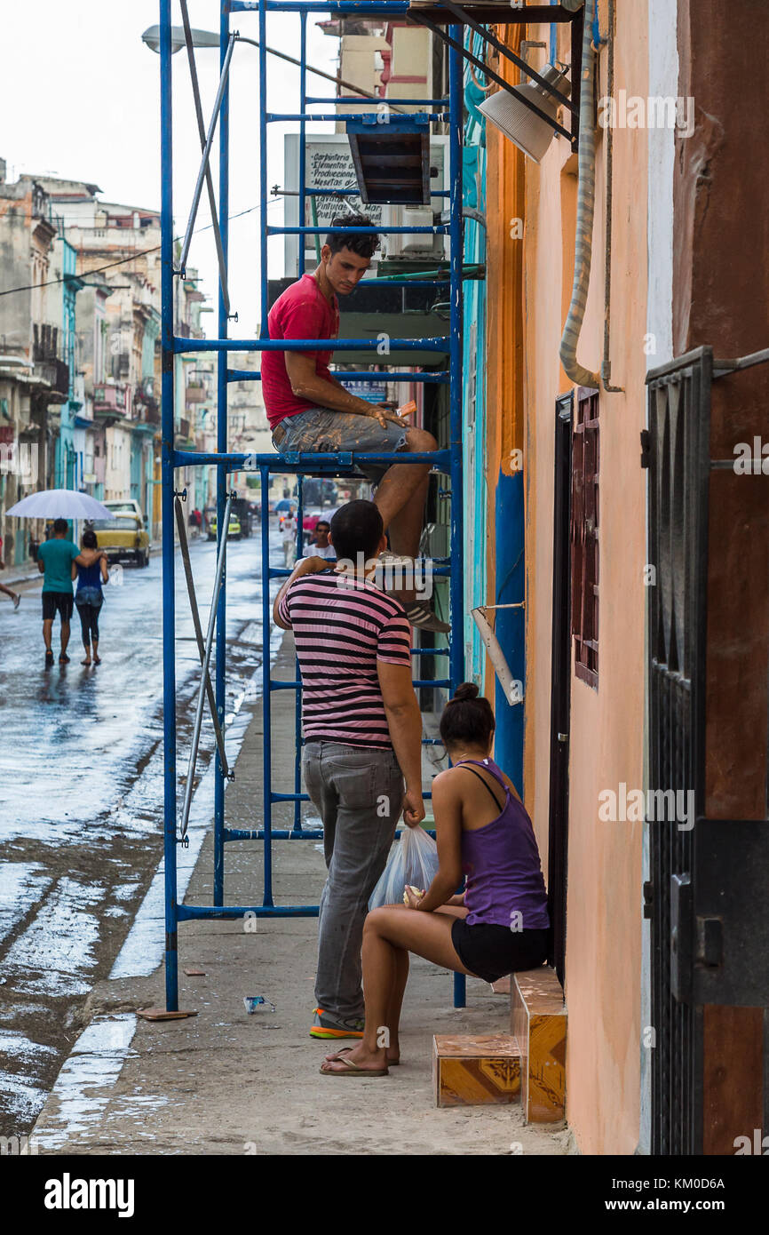 Un homme s'arrête sur un échafaudage mobile unité pour parler à des amis lors d'un travail de décoration à l'extérieur d'une maison à Centro Havana, vu au cours du mois de novembre Banque D'Images