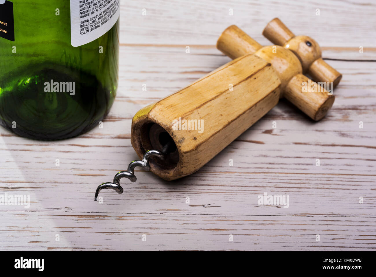 Tire-bouchon en bois ancien, rétro, en détresse sur table en bois avec une bouteille de vin vide. Banque D'Images