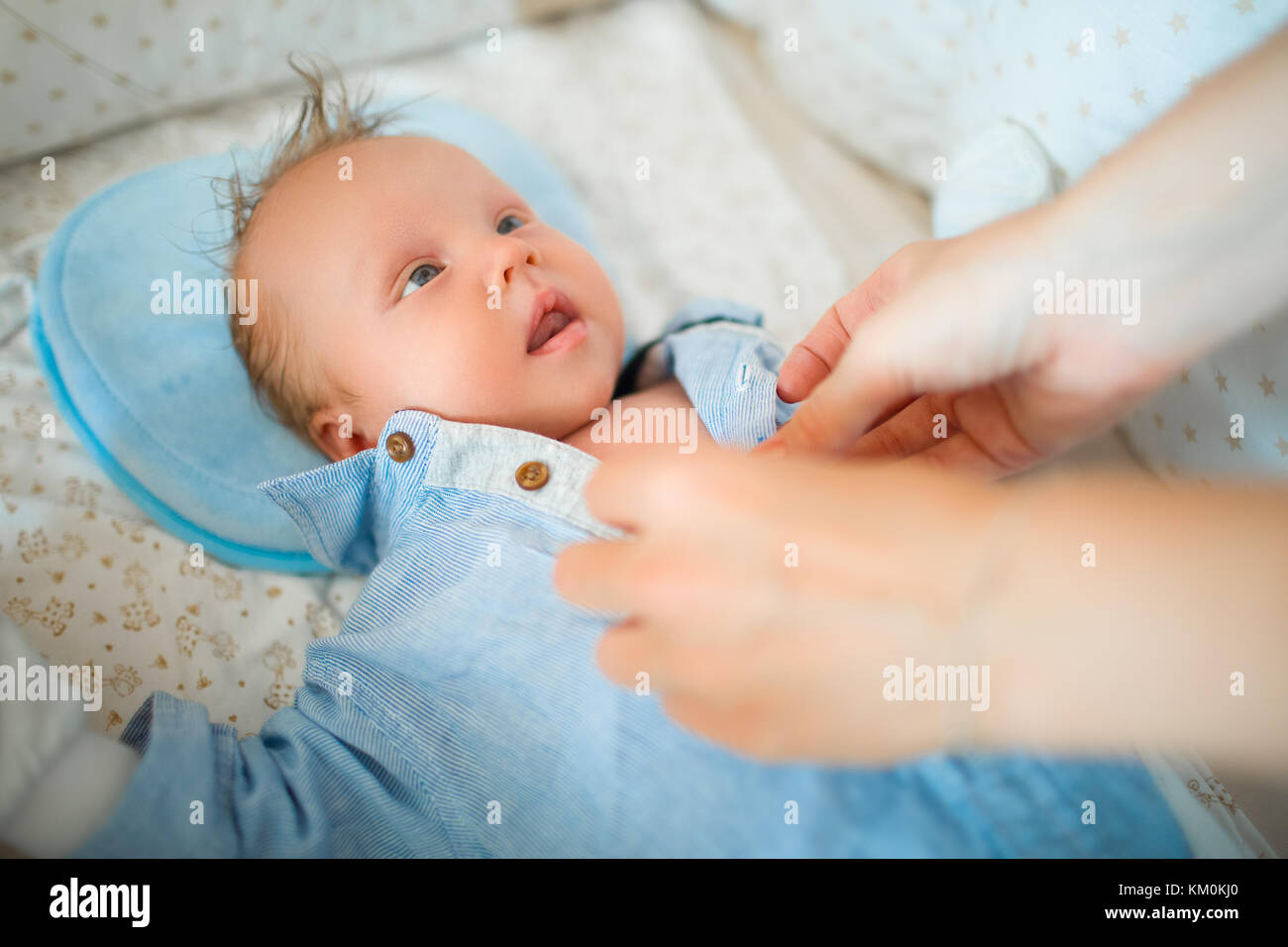 Robes de mère de son bébé, un nouveau-né se trouve dans la crèche Banque D'Images