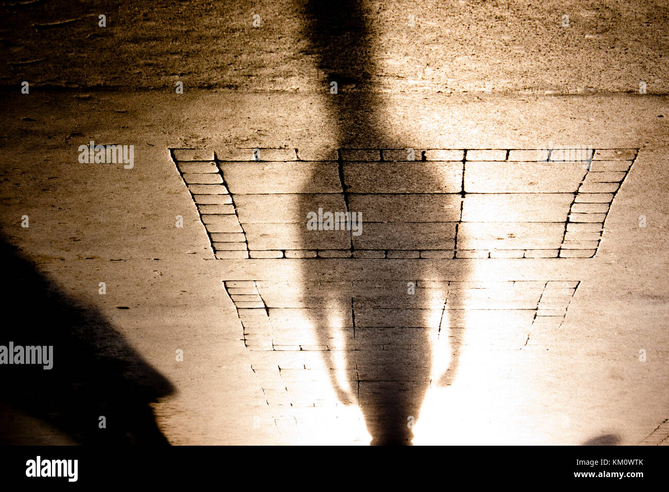 Silhouette d'ombre d'une personne sur le trottoir à motifs en sépia Noir et blanc à l'envers Banque D'Images