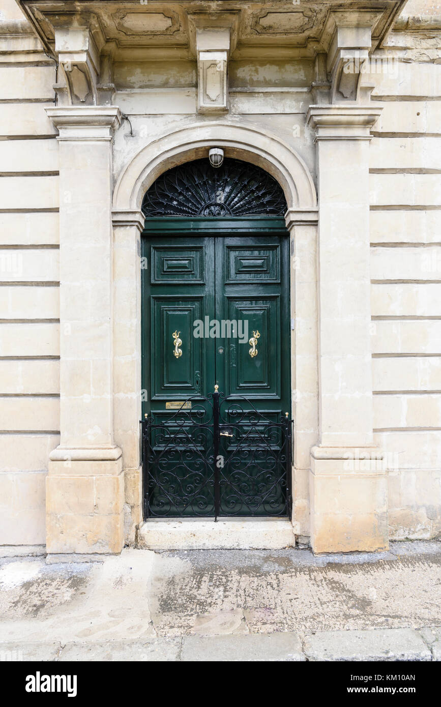 Porte en bois maltais avec de la peinture fraîche et portes de meubles en laiton poli. Banque D'Images