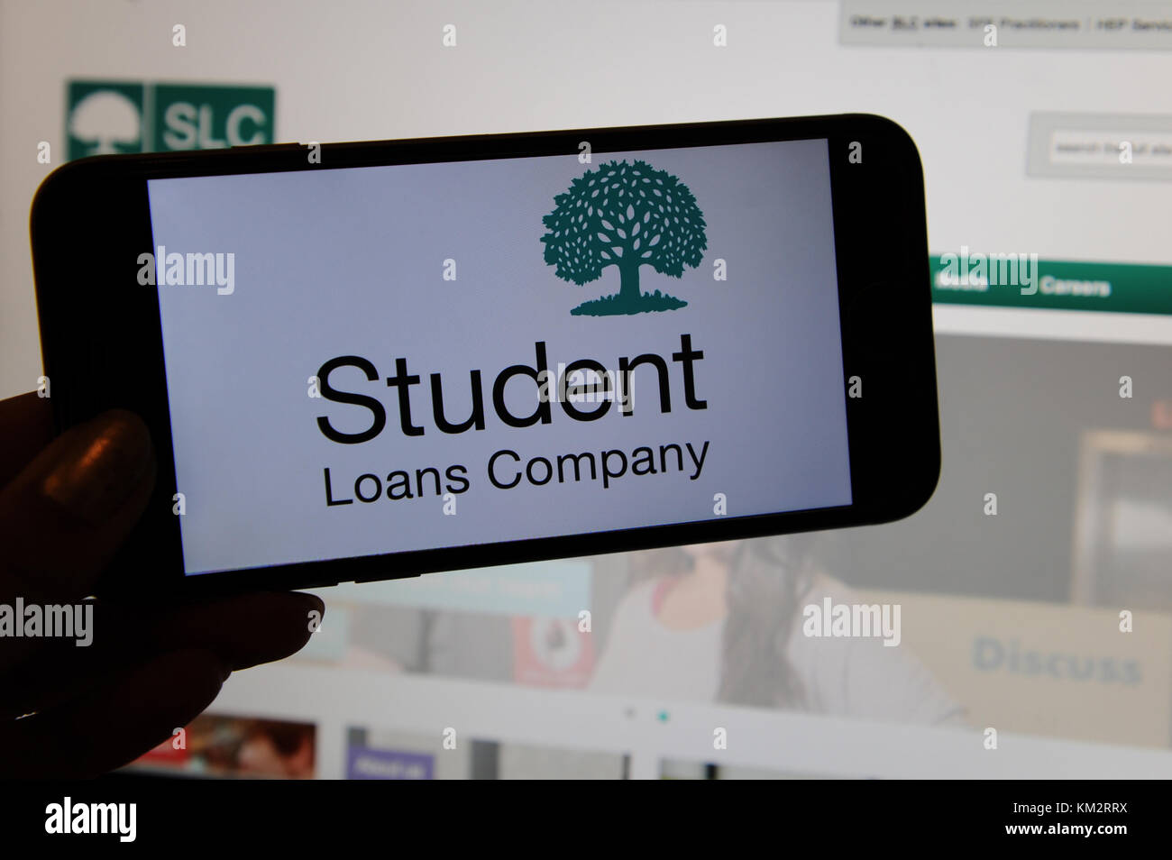 Les prêts aux étudiants, le logo de la société sur un téléphone avec le site web sur un écran d'ordinateur Banque D'Images