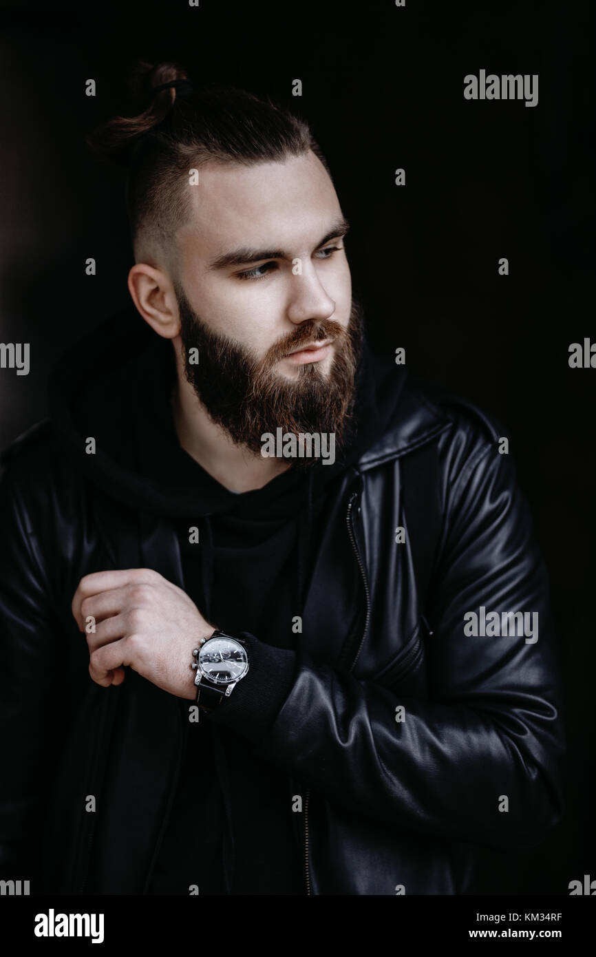 Jeune homme barbu moderne en noir vêtements de style l'article en contexte urbain. Banque D'Images Jeune homme barbu moderne en noir vêtements de style l'article en contexte urbain. Banque D'Images