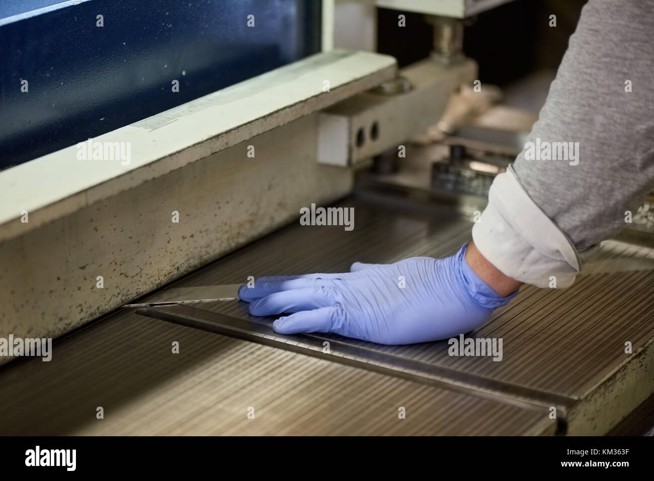 Travailleur est poussant une feuille de métal. Banque D'Images