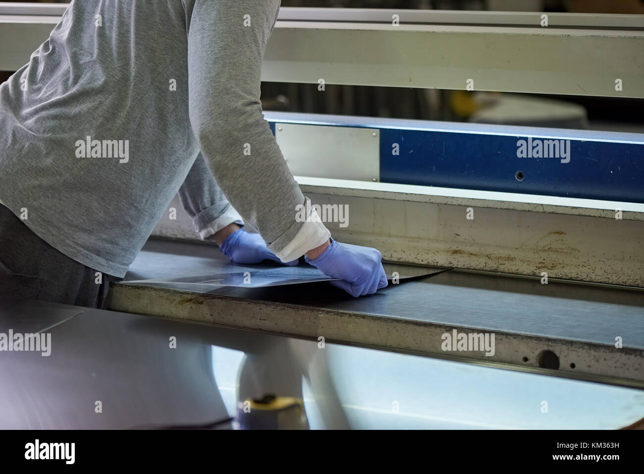 L'homme est d'estoc une feuille de métal dans une fente. Banque D'Images