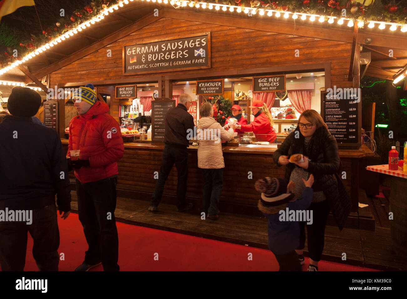 Les visiteurs à Edinburgh's Christmas event dans les jardins de Princes Street, et debout à côté d'acheter d'une food vendant les saucisses allemandes et des hamburgers. Banque D'Images
