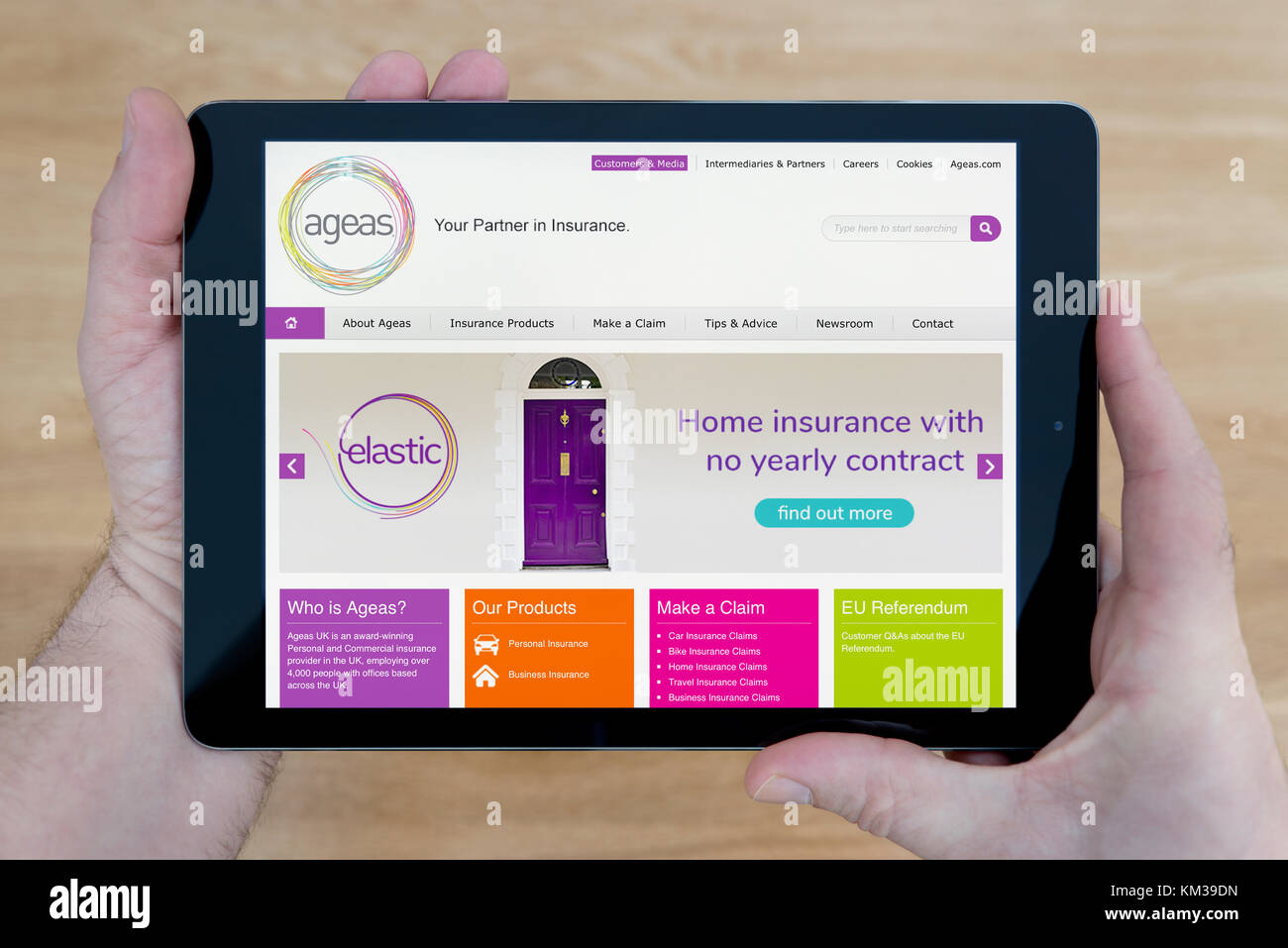 Un homme regarde l'Ageas Insurance Company site sur son iPad tablet device, tourné contre une table en bois page contexte (usage éditorial uniquement) Banque D'Images