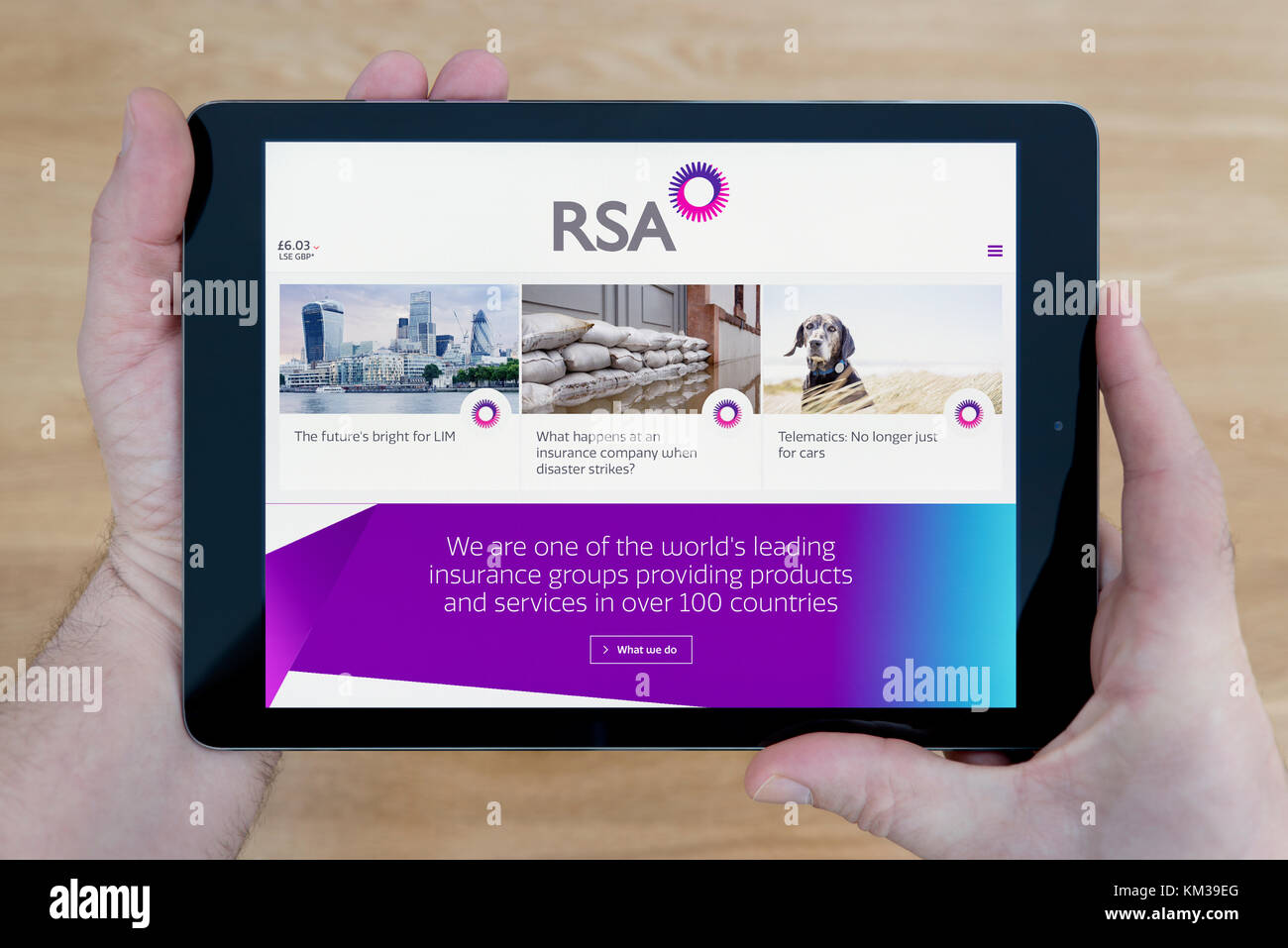Un homme regarde le RSA Insurance site sur son iPad tablet device, tourné contre une table en bois page contexte (usage éditorial uniquement) Banque D'Images