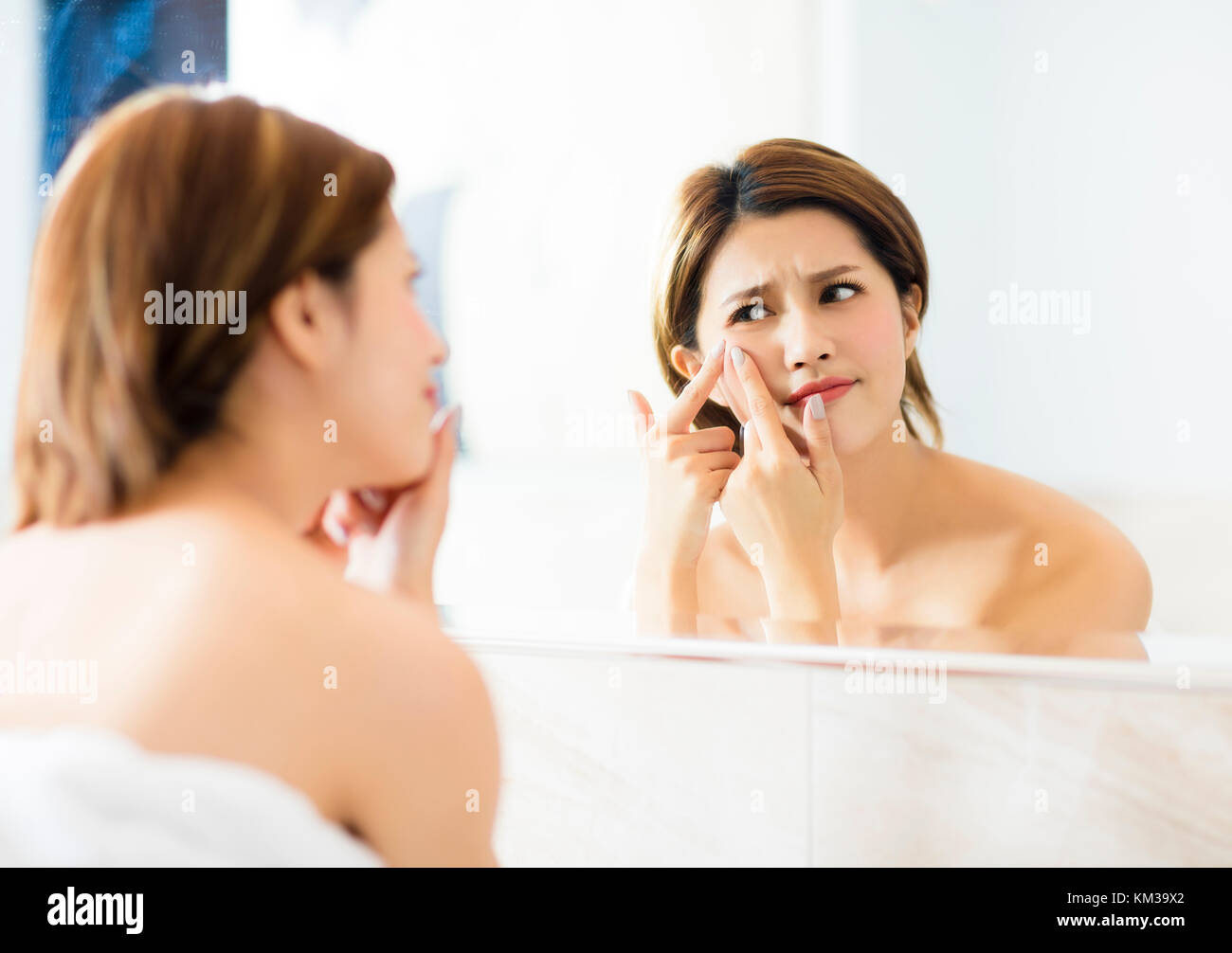 Jeune femme serrer l'acné en face du miroir Banque D'Images