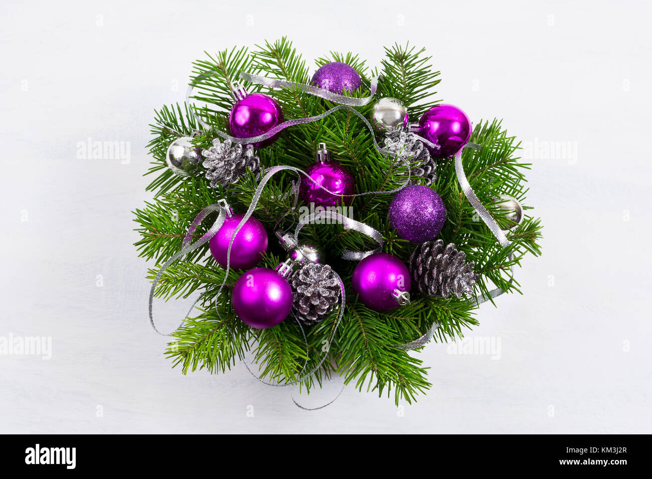 Couronne porte de Noël avec des branches de sapin, des pommes de pin décorées d'argent, paillettes et boules rouges. Banque D'Images