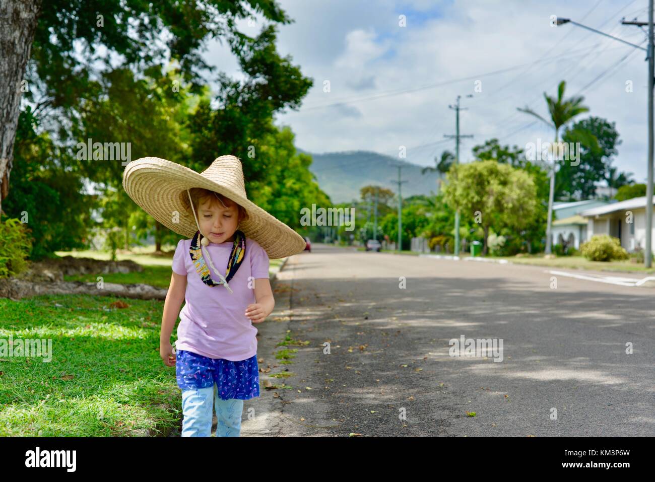 Jeune fille portant un sombrero marche dans une rue de banlieue, Townsville, Queensland, Australie Banque D'Images