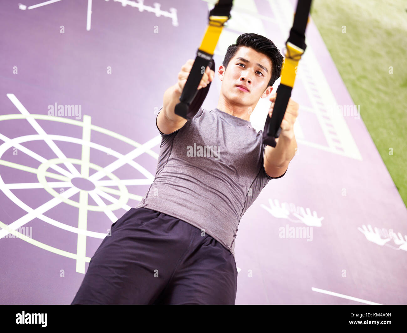 Young Asian man exercising in fitness remise en forme à l'aide de sangles. Banque D'Images