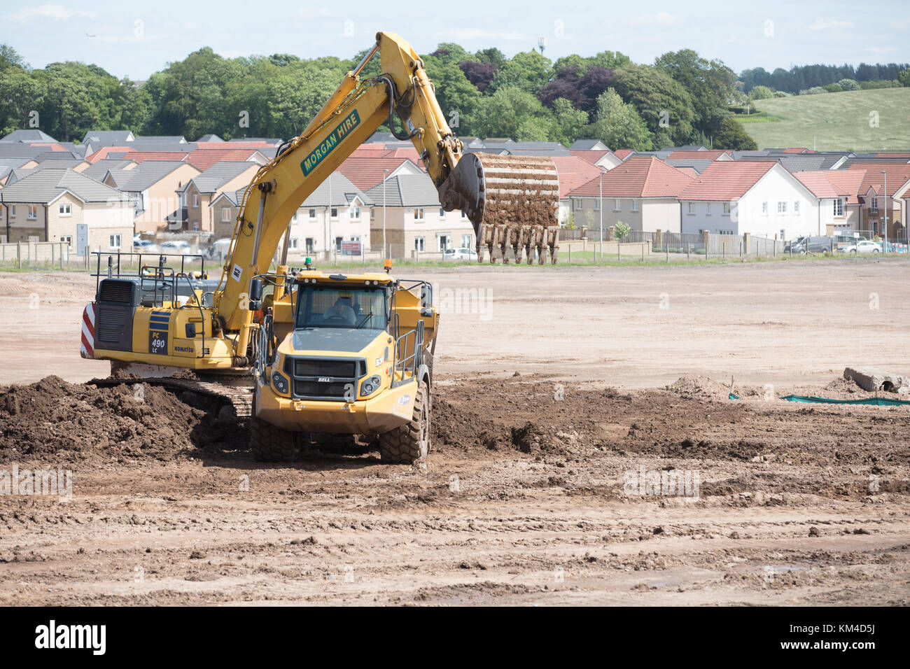 La construction de maisons sur une friche industrielle à Bishopton, Ecosse montrant de nouvelles maisons, terres défrichées et diggers préparer le terrain Banque D'Images