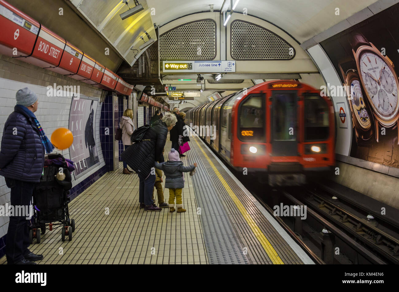 Un train arrive dans Bond street station sur le métro de Londres comme une dame avec de jeunes enfants montres. Banque D'Images