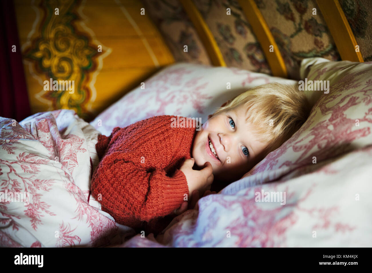 Un garçon au lit sous un archet courbe haut toit d'une roulotte, regardant la caméra. Banque D'Images