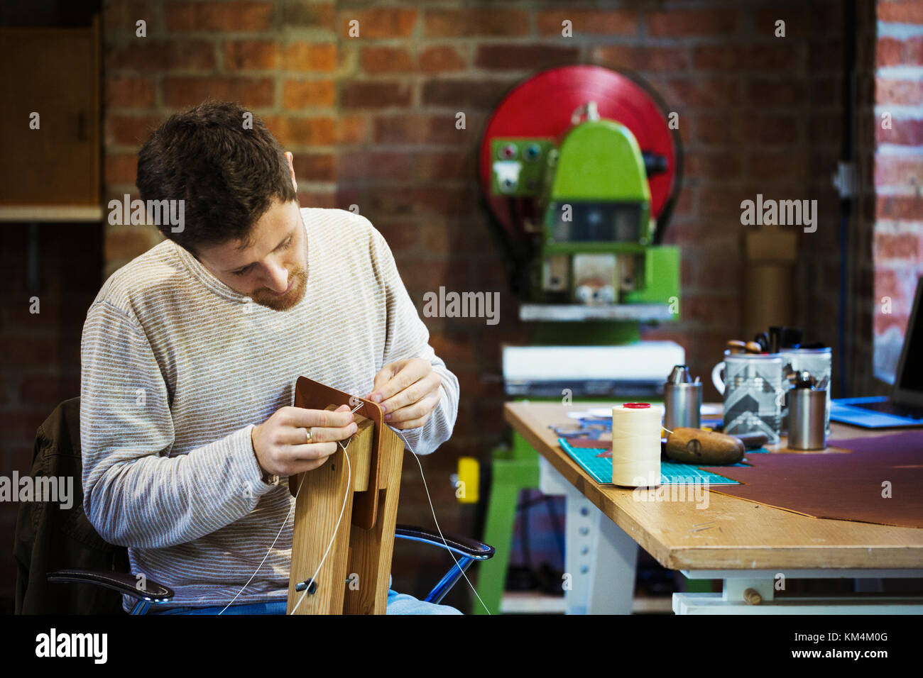 Un artisan dans un atelier, ou cordon d'Enfilage ficelle à travers un petit objet fait main. Banque D'Images
