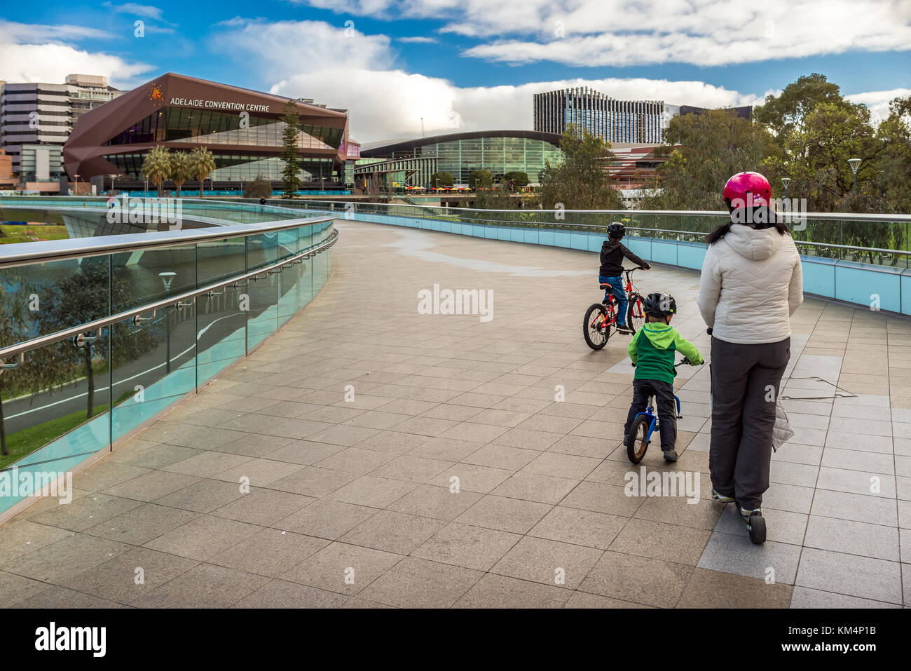 Adelaide, Australie - Août 27, 2017 : mère avec deux fils ridind bicyclettes le long de la passerelle dans la ville d'Adelaïde Torrens sur une journée Banque D'Images