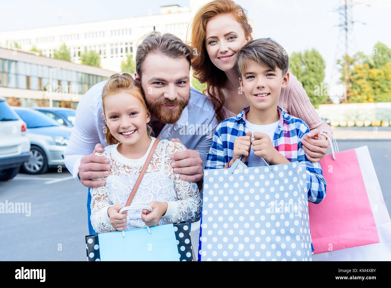 Les parents hugging children with shopping bags Banque D'Images
