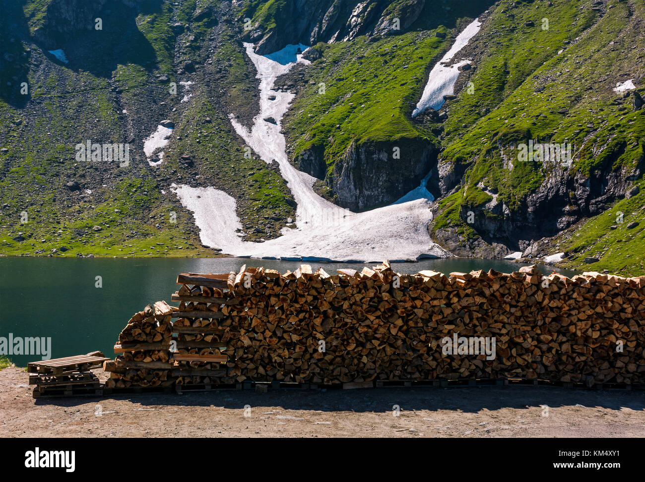 Bois de chauffage coupé sur le bord d'un glacier. été magnifique paysage de montagnes. rocky hill avec de l'herbe et des taches de neige. Banque D'Images