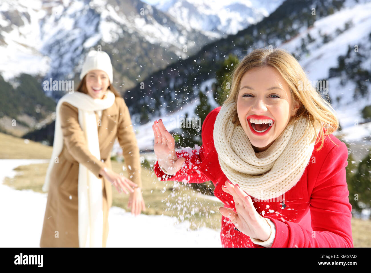 Deux amis plaisanter lançant des boules de neige en vacances dans une montagne enneigée en hiver Banque D'Images
