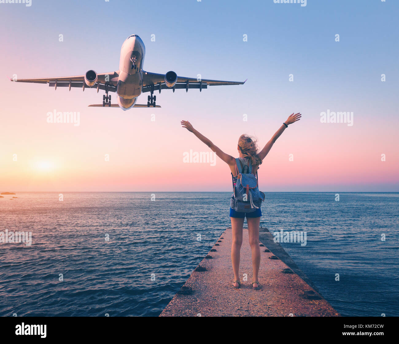 Avion et femme heureuse au coucher du soleil. paysage estival avec girl se tenant sur la mer pier avec les armes et l'avion passager. femme et l Banque D'Images