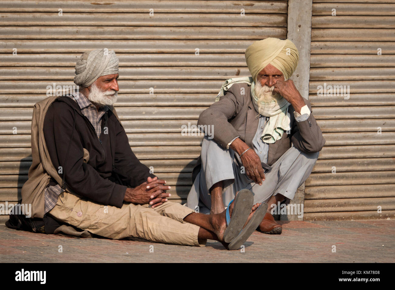 Deux hommes sikh punjabi avec barbe blanche et turban assis à parler dans la rue, à Amritsar, Punjab Banque D'Images