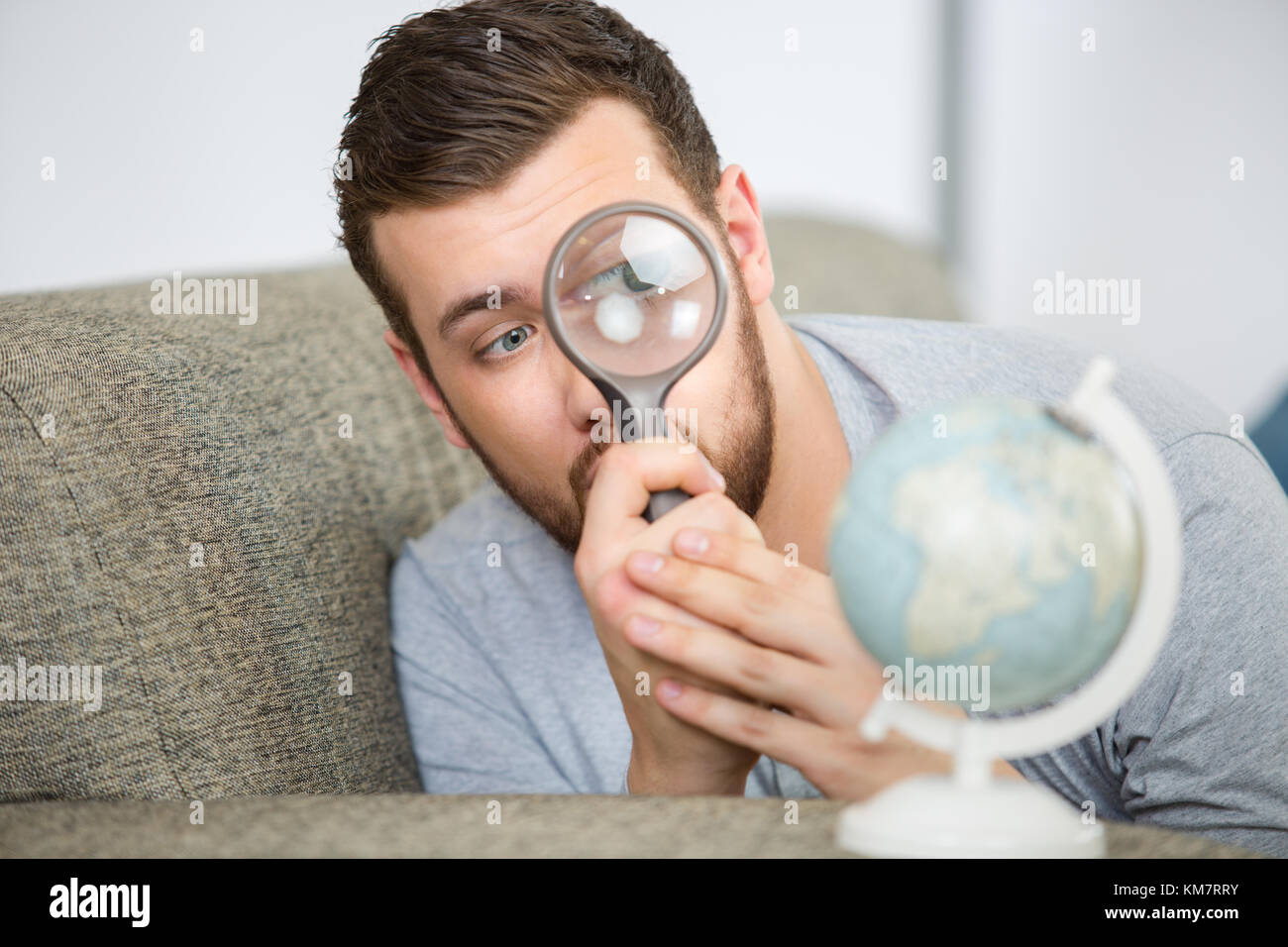 Compte tenu de l'homme un globe terrestre avec une loupe Banque D'Images