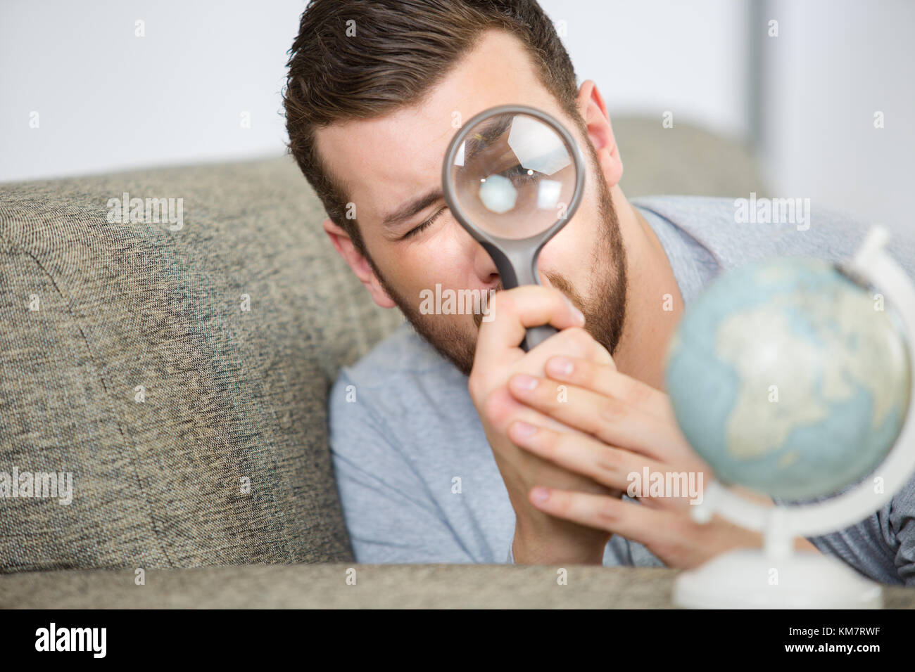 Compte tenu de l'homme un globe terrestre avec une loupe Banque D'Images