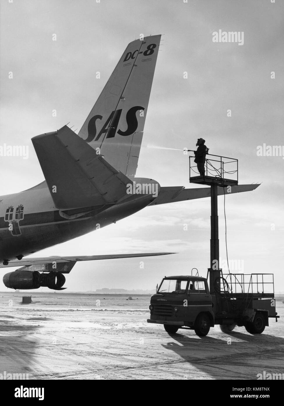 Un Douglas DC-8 Scandinavian Airlines System (SAS) subissant des procédures de dégivrage dans un aéroport dans les années 1960 Le dégivrage est essentiel pour assurer la sécurité des aéronefs pendant les opérations hivernales en éliminant l'accumulation de glace sur les surfaces critiques. Banque D'Images