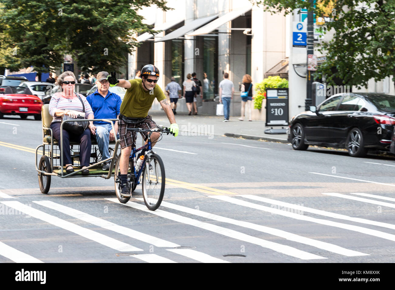 Seattle, Washington, USA - Septembre 5th, 2017 : un mâle pedicab se lève sa main pour lui dire bonjour le transport de passagers dans son tricycle au downtown Banque D'Images