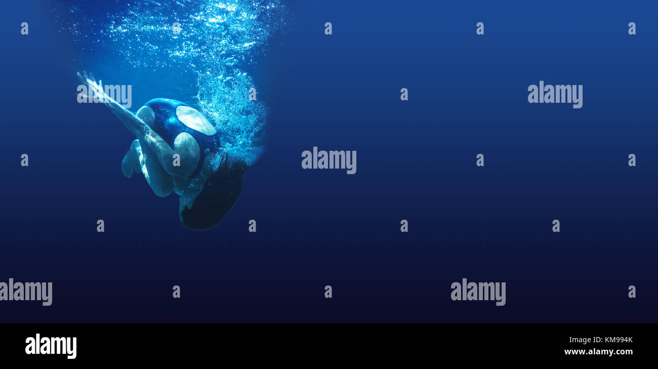 L'homme nage dans l'eau d'un bleu profond Banque D'Images