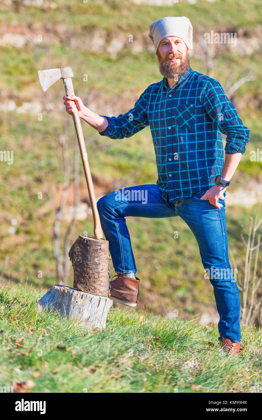 Jeune bûcheron avec barbe tient sa hache à la main. Banque D'Images