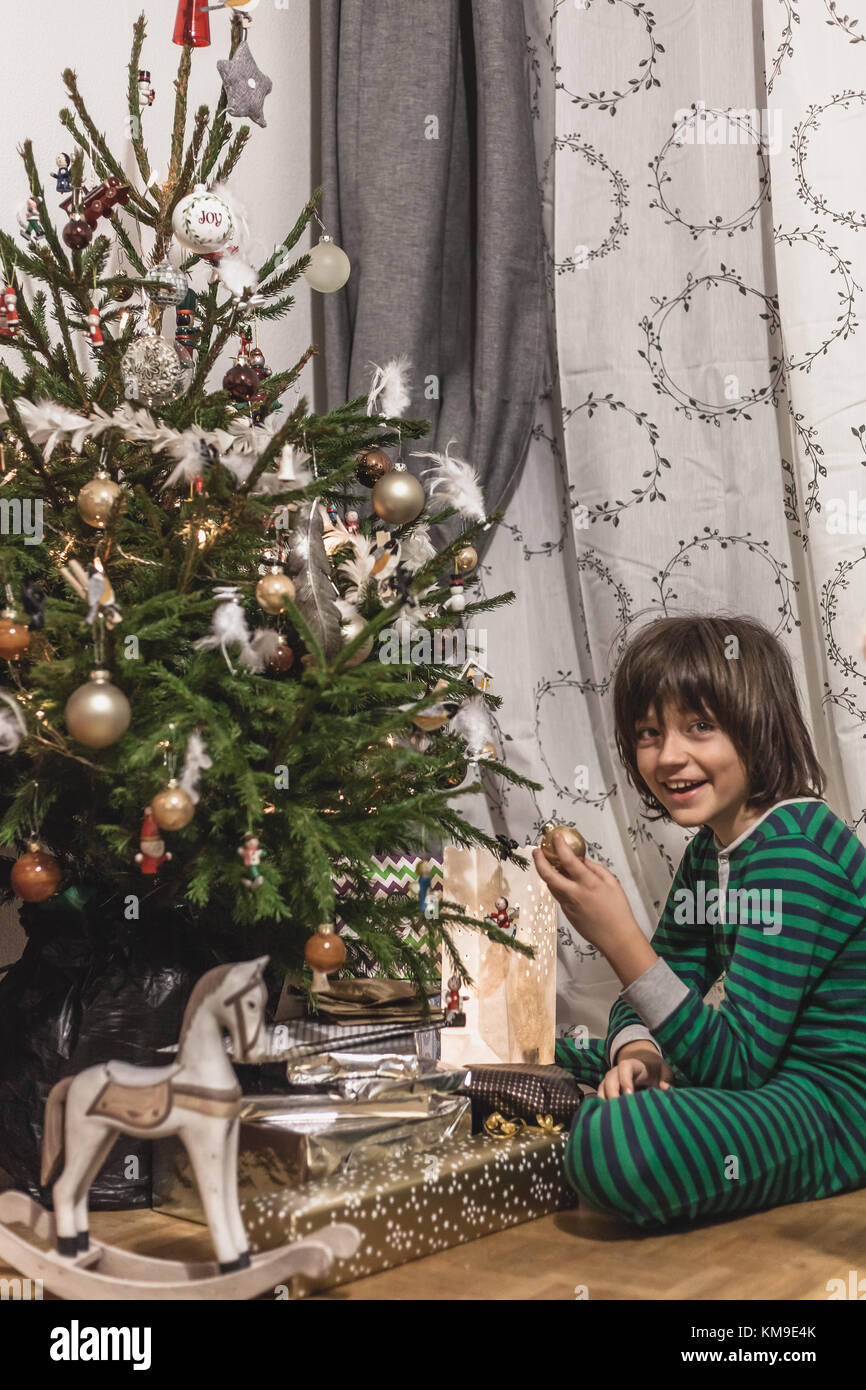 Dans son pyjama garçon assis par un arbre de Noël Banque D'Images