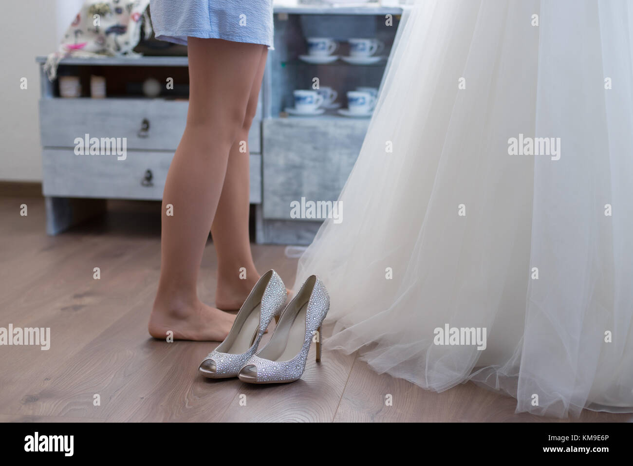 Bride standing à côté de sa robe de mariage et chaussures de mariage Banque D'Images