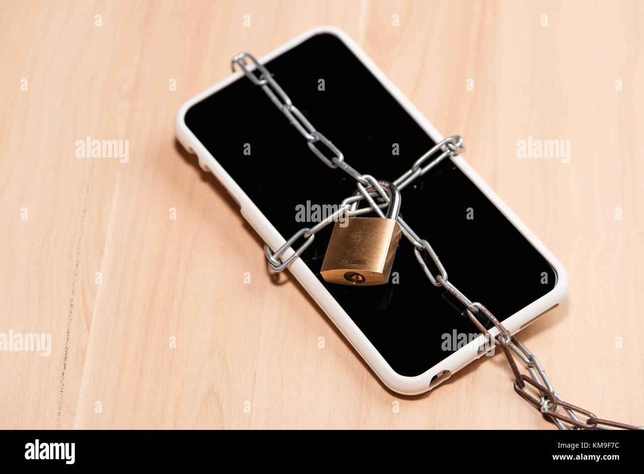 Chaîne liée smartphone avec verrouillage sur table en bois. Banque D'Images