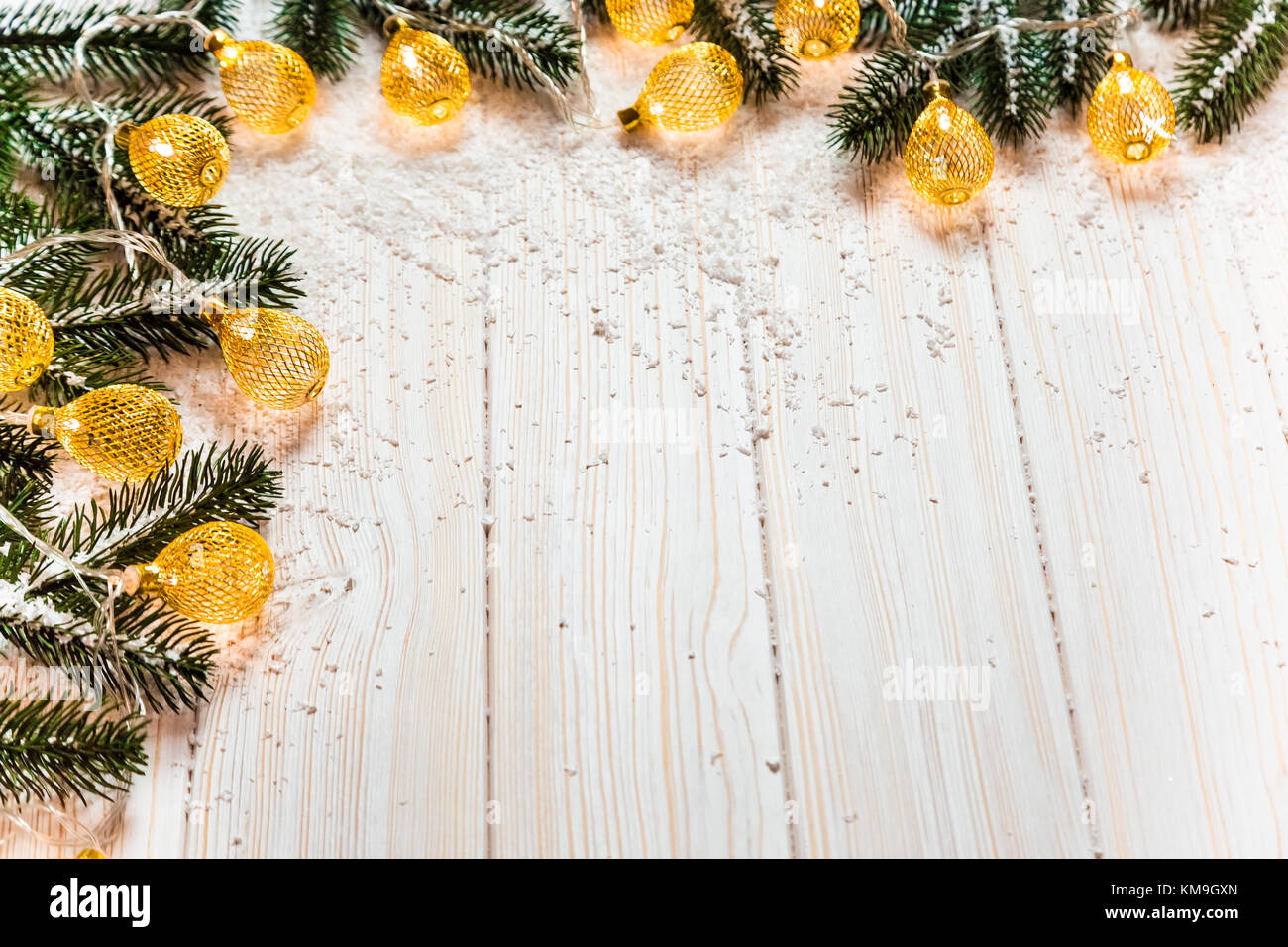 Noël arrière-plan avec une guirlande lumineuse blanche sur table en bois avec les branches de l'arbre de Noël et la neige. Une belle maison de vacances idée de wint Banque D'Images