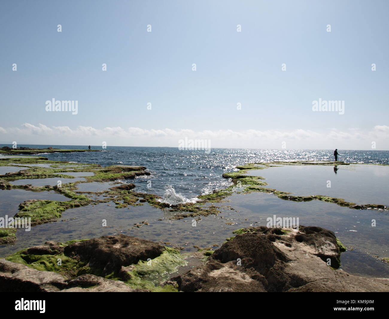 Debout sur la falaise, pêcheur avec sa canne à pêche sur le fond de l'horizon et le ciel bleu au-dessus Banque D'Images