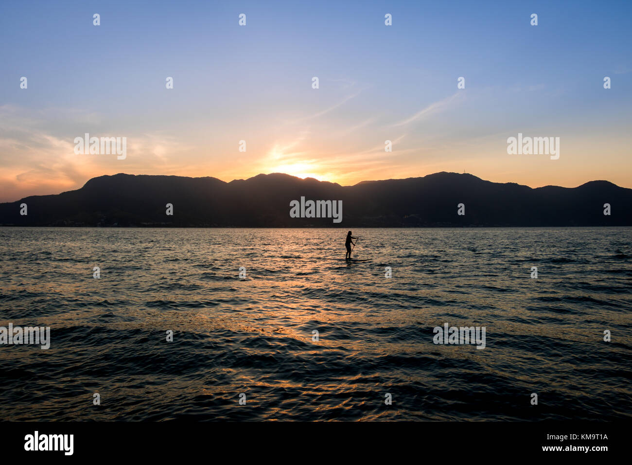 Stand up paddle au coucher du soleil avec Sao Sebastiao sur fond - Ilhabela, Sao Paulo, Brésil Banque D'Images