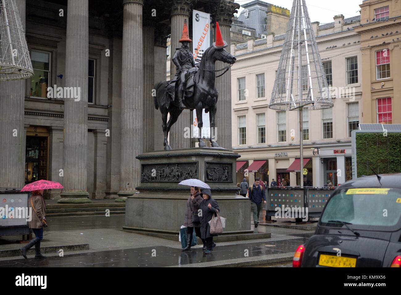 Météo France : jour de pluie que les gens magasinent à travers la ville. L'extérieur de Goma et l'homme à la tête de la statue du duc d'Édimbourg Banque D'Images