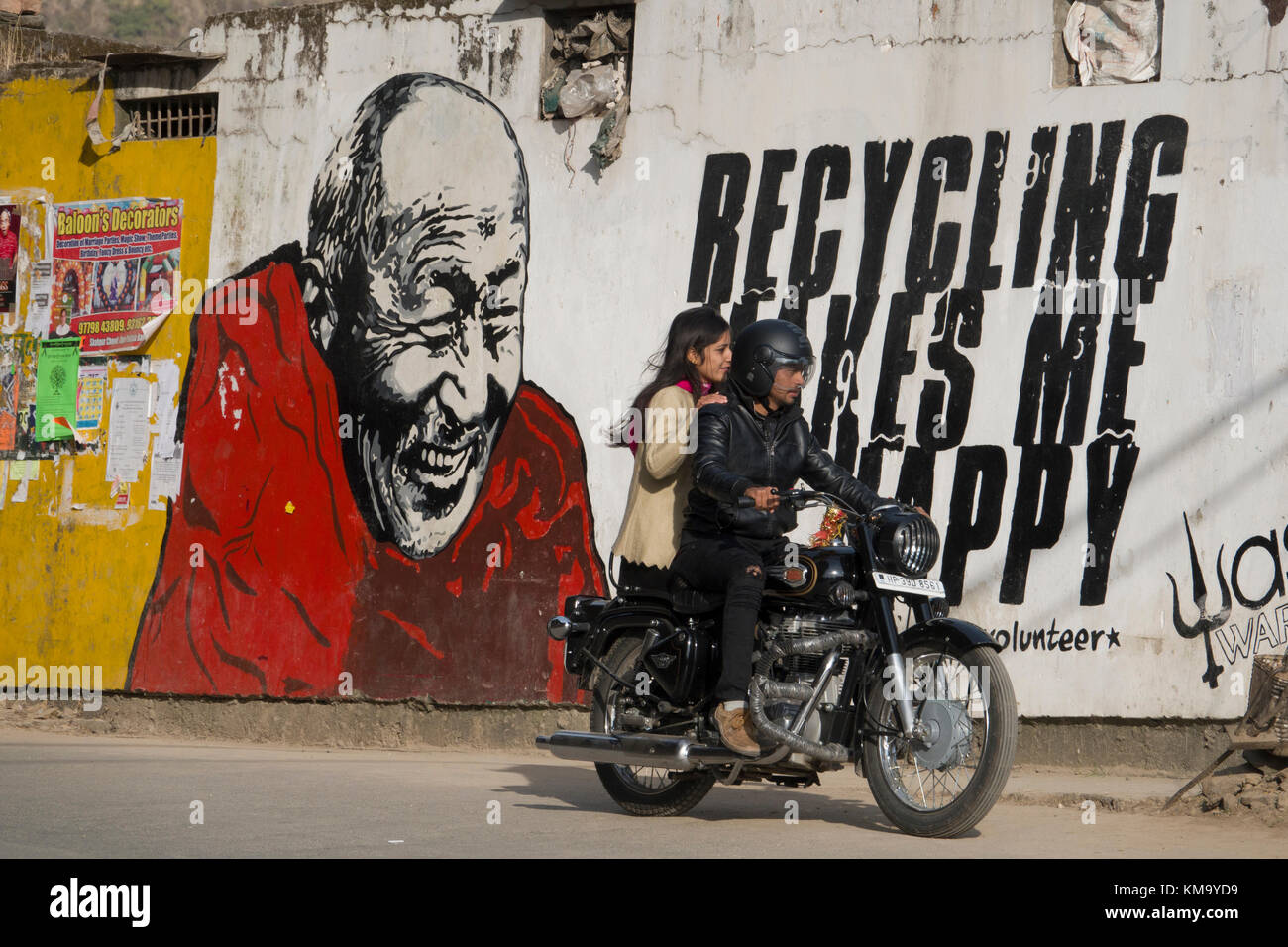 Couple sur moto ride passé sur la construction murale montrant le moine bouddhiste à côté de message de recyclage Banque D'Images