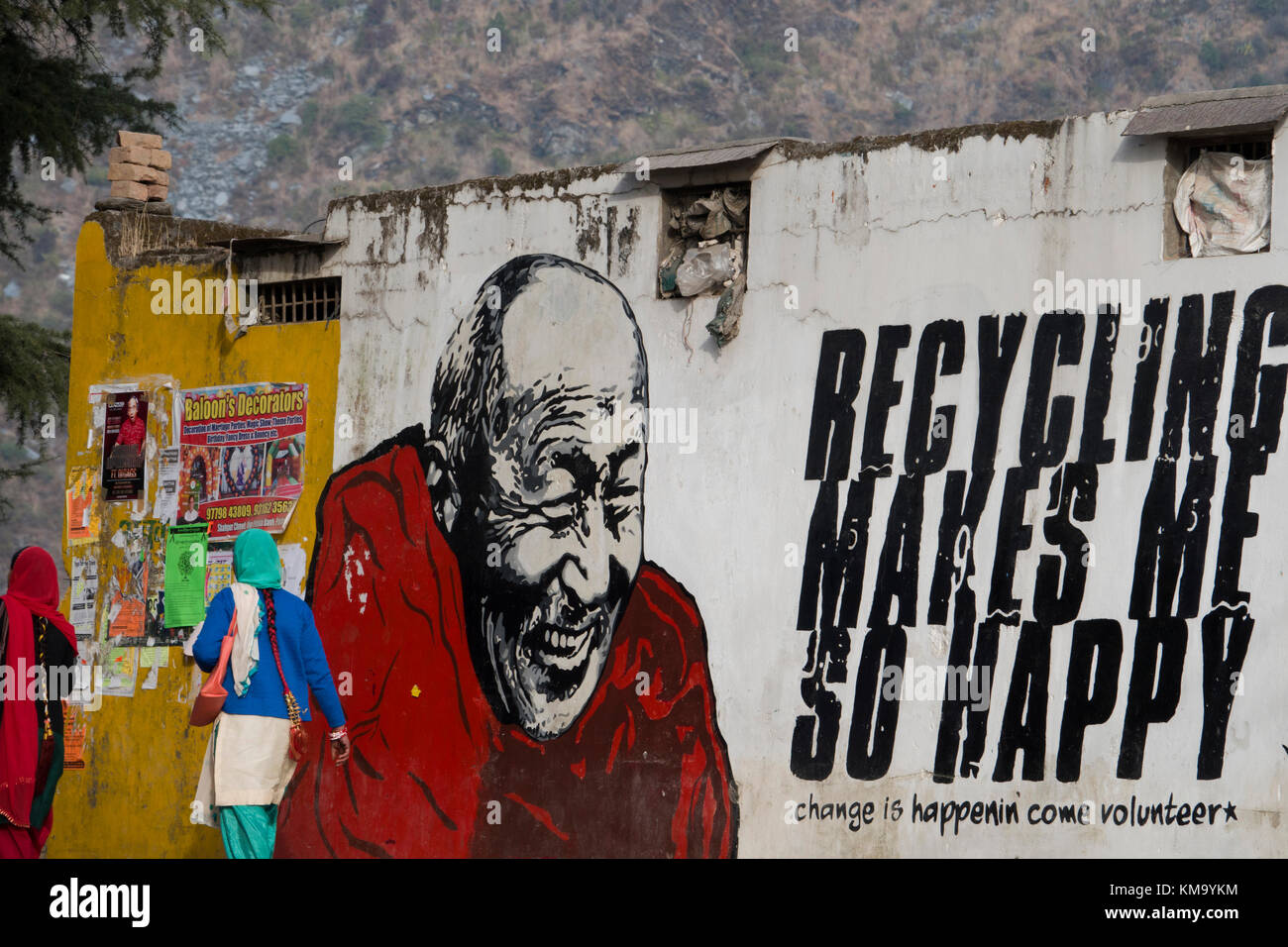 Les gens à pied passé sur la construction murale montrant le moine bouddhiste à côté de message de recyclage Banque D'Images