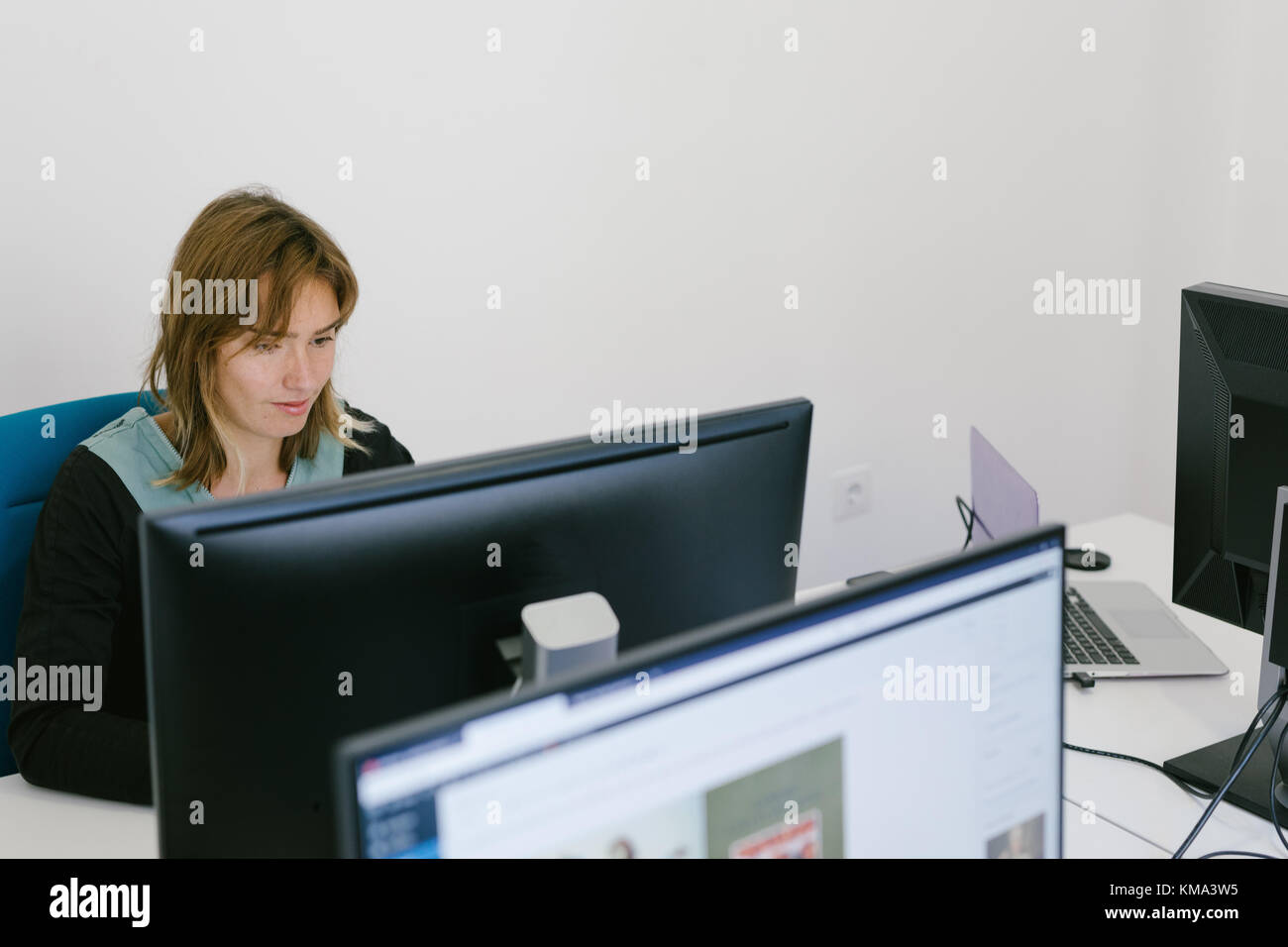 Jolie Jeune femme assise et de travail à l'ordinateur de bureau. Banque D'Images