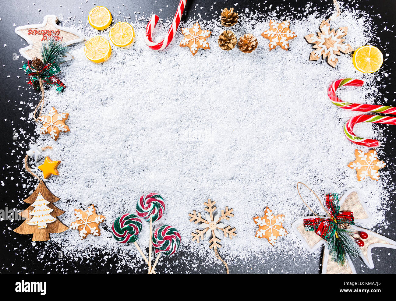 Fond de Noël avec des flocons de neige blanc, d'épices, des jouets, des bonbons au citron, et nouvel an vacances d'hiver. Décor cadre sur une table en bois noir Banque D'Images
